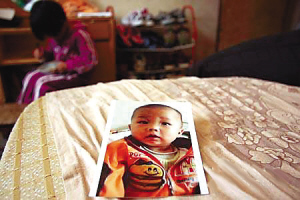 ↑父亲拿着儿子的照片，欲哭无泪。